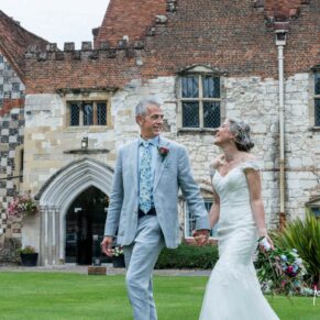 The smiling newlyweds take a stroll at the front of Bisham Abbey on their wedding day