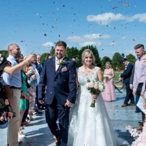 The newlyweds dash through the colourful confetti at their Cotswolds Hotel, Golf and Spa wedding
