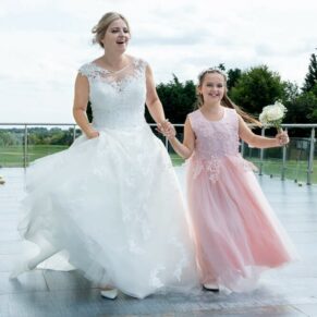 The bride dashes across the terrace with her flower girl for a photography opportunity at her Cotswolds Hotel, Golf and Spa wedding