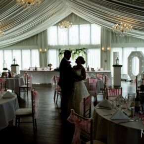 A silhouette photography shot of the newlyweds inside the marquee at their Cotswolds Hotel, Golf and Spa wedding