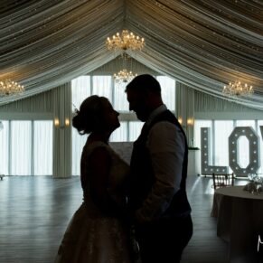 Dramatic silhouette pose of the bride and groom inside the marquee at their Cotswolds Hotel, Golf and Spa wedding