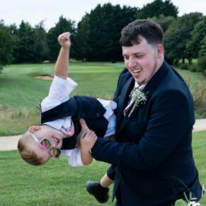 An usher is captured larking around for this photography opportunity at this wedding with his son at The Cotswolds Hotel, Golf and Spa venue