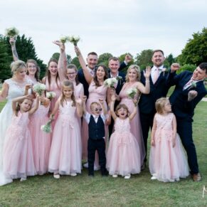 The wedding bridal party gather for a photo on the lawns at Cotswolds Hotel, Golf and Spa