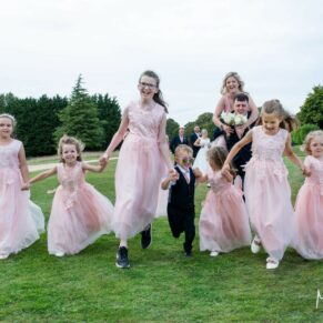 The giggling pageboy and flower girls run towards the camera for a photography opportunity at this summer Cotswolds Hotel, Golf and Spa wedding