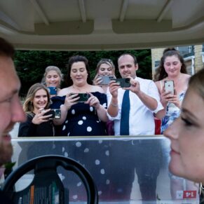 Paparazzi photography opportunity as wedding guests capture the newlyweds inside a golf buggy at their Cotswolds Hotel, Golf and Spa wedding