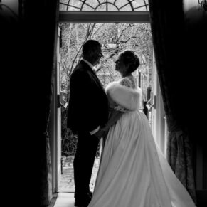 Silhouette pose of the newlyweds in the arched doorway straight after their civil ceremony at their Kings Chapel wedding reception