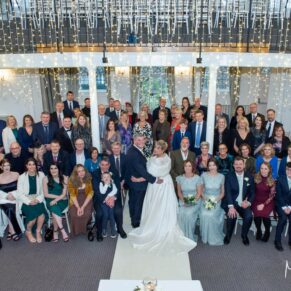 Group pose of all the guests captured from the balcony at their Kings Chapel wedding reception in Old Amersham