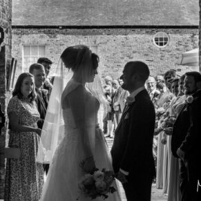 A silhouette shot of the newlyweds as they exit their Meols Hall wedding ceremony into the courtyard