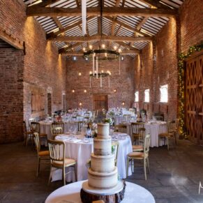 The wedding cake captured with the barn interiors of Meols Hall in the background