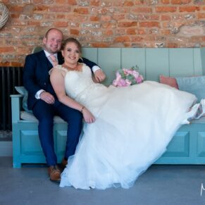The bride and groom relax on a bench at their Meols Hall wedding