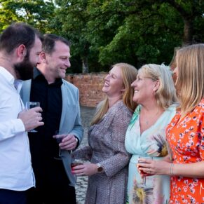 A group of wedding guests enjoy the lively banter in the courtyard at Meols Hall