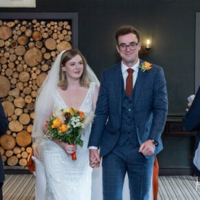 The smiling couple exit the indoor ceremony at the hotel