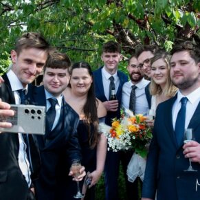 Selfie time for the newlyweds with a group of friends at their Manor House Hotel wedding reception in Moreton-in-Marsh