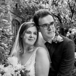 A classic style black and white portrait of the bride and groom in the gardens of their Manor House Hotel wedding reception in Moreton-in-Marsh