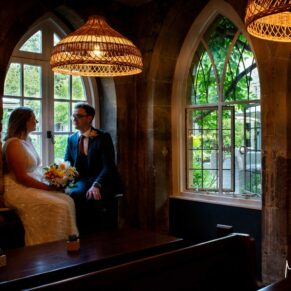 The historic interiors of the Manor House Hotel in Moreton-in-Marsh are stunning for photo-opportunities, this image featuring these striking arched windows was captured in the bar area. The combination of the windows and rustic interiors worked perfectly for this silhouette pose of the newlyweds. Compositions don't get much better than this for absolute wow factor results on your wedding day. A dramatic capture of the newlyweds sat in a feature window inside their Manor House Hotel wedding venue in Moreton-in-Marsh