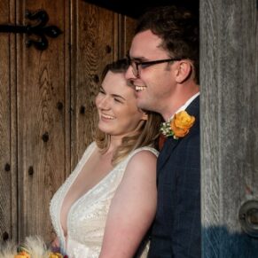 The newlyweds pose for a picture in the entrance doorway at their Manor House Hotel wedding reception in Moreton-in-Marsh