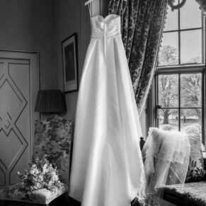 The bride's gorgeous gown captured hanging in a window prior her Chenies Manor civil wedding ceremony