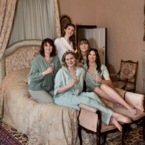 The bride in in the bridal suite sat on the half tester bed with her mother and bridesmaids prior to her Chenies Manor civil wedding ceremony