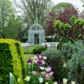 The outdoor ceremony area and rose arbour at Chenies Manor captured through the colourful flower borders