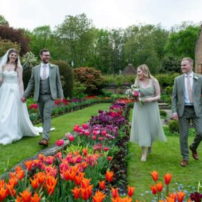 The newlyweds take a stroll through the colourful tulips with their bridesmaid and best man at their Chenies Manor wedding reception