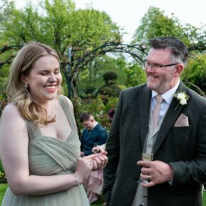 Candid moment captured between the bride's father and the bridesmaid at Chenies Manor wedding during the drinks reception