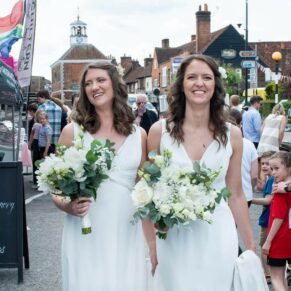 The bride and bride bravely take a stroll through the busy market in the nearby High Street soon after their Kings Chapel's Old Amersham wedding ceremony