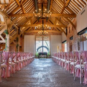 Photography of stunning pink themed barn wedding venue interior all set for the civil ceremony at this fabulous Buckinghamshire venue