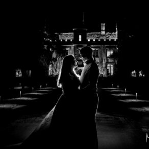 Dramatic black and white photography of bride and groom silhouetted after night fall on the driveway at their historic Buckinghamshire wedding venue