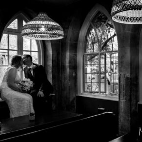 Black and white wedding photography of bride and groom sat in a period feature window at their Buckinghamshire venue