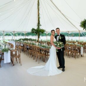 Buckinghamshire photography of a summer festival style rustic wedding marquee interior with the newlyweds in the foreground
