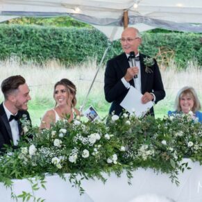 Buckinghamshire photography of the speeches in full flow inside a summer festival style rustic wedding marquee