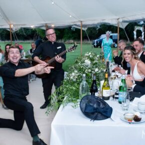 Buckinghamshire wedding photography of the newlyweds being entertained in their marquee by the energetic singing waiters