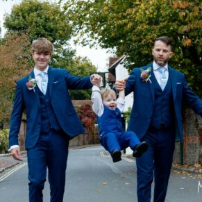 Relaxed photography pose of the groom and the usher swinging the giggling pageboy during the wedding drinks reception at this Buckinghamshire pub