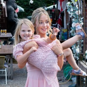 Relaxed photography pose of the bridesmaid carrying the flower girl over the bridge during the wedding drinks reception at this Buckinghamshire pub