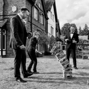 Photography of the ushers playing Jenga in the gardens at this Buckinghamshire pub wedding