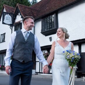 Photography of the newlyweds taking a stroll at their Buckinghamshire pub wedding in front of the historic building