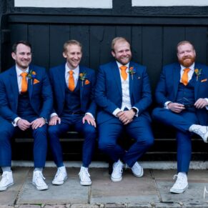 Photography of groom and his ushers casually sat on an old bench at his Buckinghamshire pub wedding pre ceremony