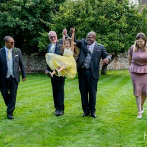 Photography of the newlyweds swinging the flower girl in the air at their Badgemore Park wedding in Oxfordshire