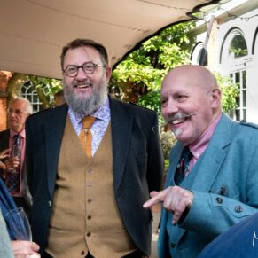 Photography of some wedding guests enjoying the banter during the courtyard drinks reception at Badgemore Park in Oxfordshire