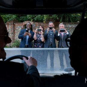 Photography of the newlyweds being snapped by the guests in the golf buggy at their Badgemore Park wedding reception in Oxfordshire