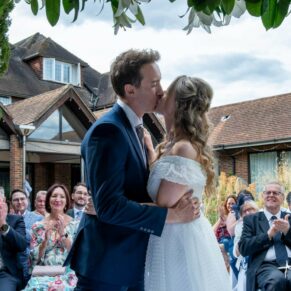 Photography of the first kiss between the newlyweds at their outdoor wedding ceremony at Fredrick's Hotel in Berkshire