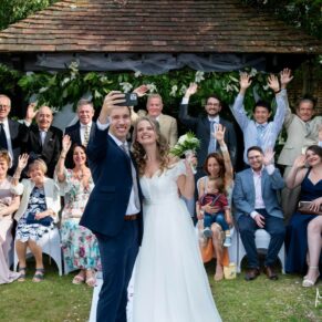 Photography of the bride and groom posing with their guests for a fun selfie in the gardens at their Fredrick's Hotel wedding in Berkshire