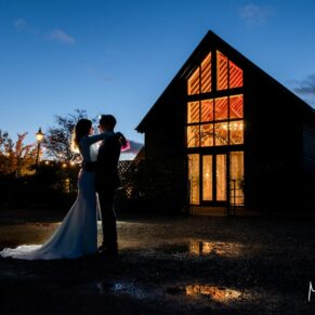 Winters Tale Country Barn wedding venue in Buckinghamshire with floodlighting used to backlight the silhouetted bride and groom for this photography pose