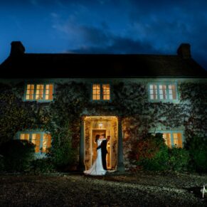 Winters Tale Country Barn wedding venue in Buckinghamshire with floodlighting used to illuminate the bride and groom in the doorway