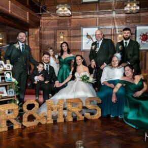 Relaxed photography pose of the newlyweds with their family in the Oak Room at their Crazy Bear Hotel winter wedding in Stadhampton