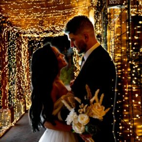 Relaxed silhouette photography pose of the newlyweds in the dramatically illuminated light tunnel at their Crazy Bear Hotel winter wedding in Stadhampton