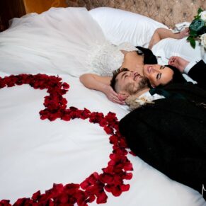 Relaxed photography of the newlyweds laying on the bed with a wonderful rose petal heart at their Crazy Bear Hotel wedding in Stadhampton